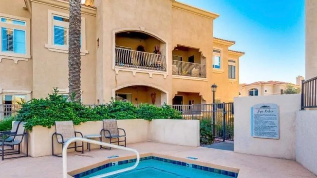 A vibrant exterior scene featuring a community swimming spa surrounded by balconies and lush greenery. Decorative signage and ample space for lounging hint at communal relaxation, sunbathing, and social interaction.