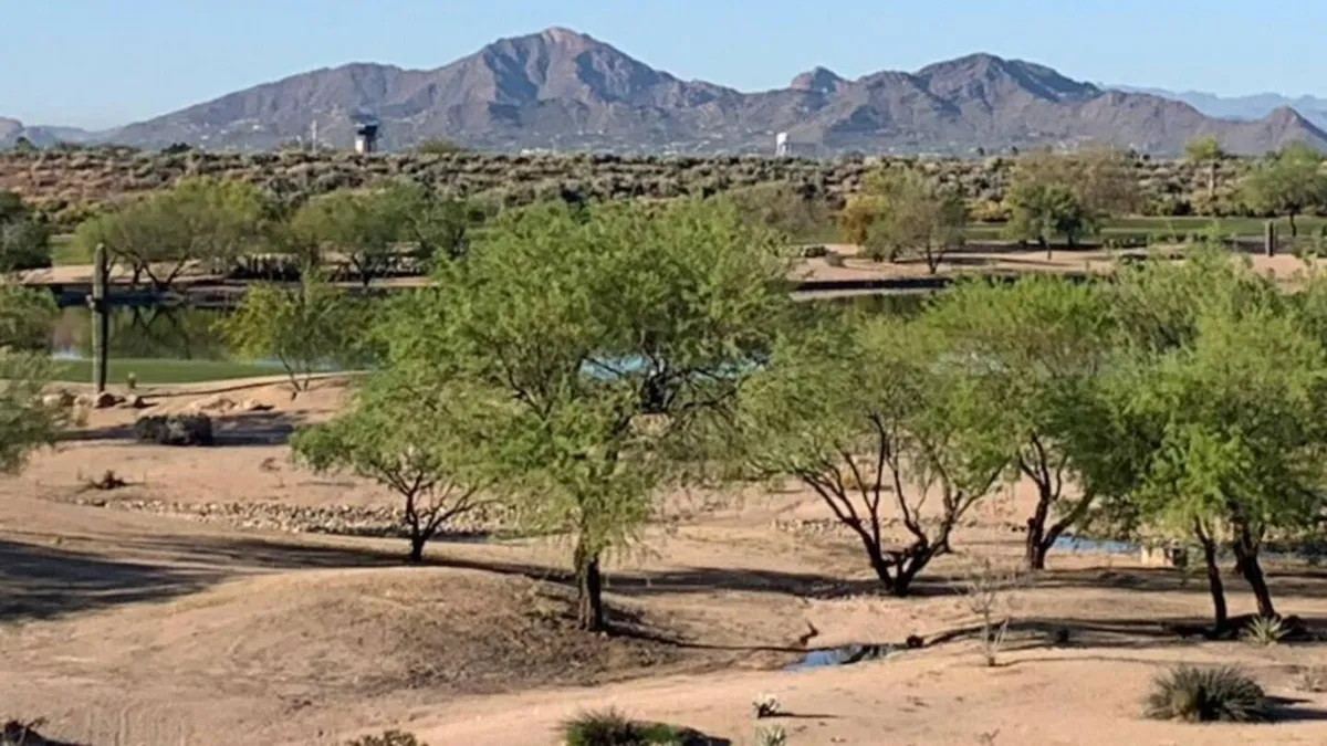 A tranquil landscape of rugged mountains, tall trees, and a peaceful water body, all bathed in soft natural light. The scene invites exploration and reflection, evoking the experience of hiking or relaxing in the nearby preserves and natural areas.